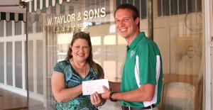 Vicki Munie accepts one of two checks from Clarendon EDC board member Jacob Fangman for improvements made to properties on Kearney Street. Enterprise Photo / Roger Estlack