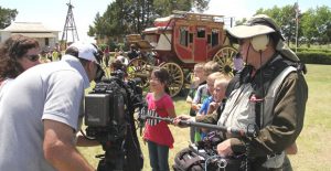 The stagecoach “Journey” sits in the background as a crew with CBS Sunday Morning interviews Clarendon Elementary students last week at the Saints’ Roost Museum. The 136-year-old stage is making its final run this week. Enterprise Photo / Roger Estlack